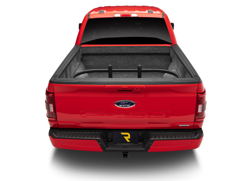 Rear view of a red pickup with the tailgate up and the BedXTender HD Max flipped forward inside the bed