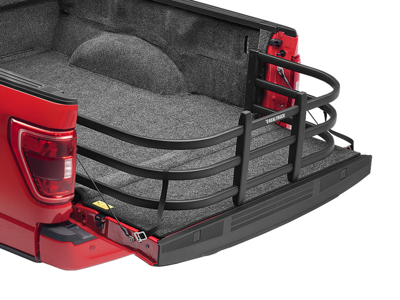 BedXTender HD Max extended over the lowered tailgate of a red pickup, close rear three-quarter studio view