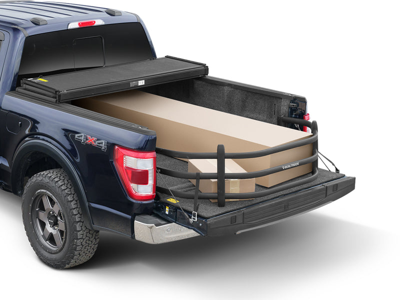 BedXTender HD Sport extended over the lowered tailgate of a dark blue pickup, holding long boxes