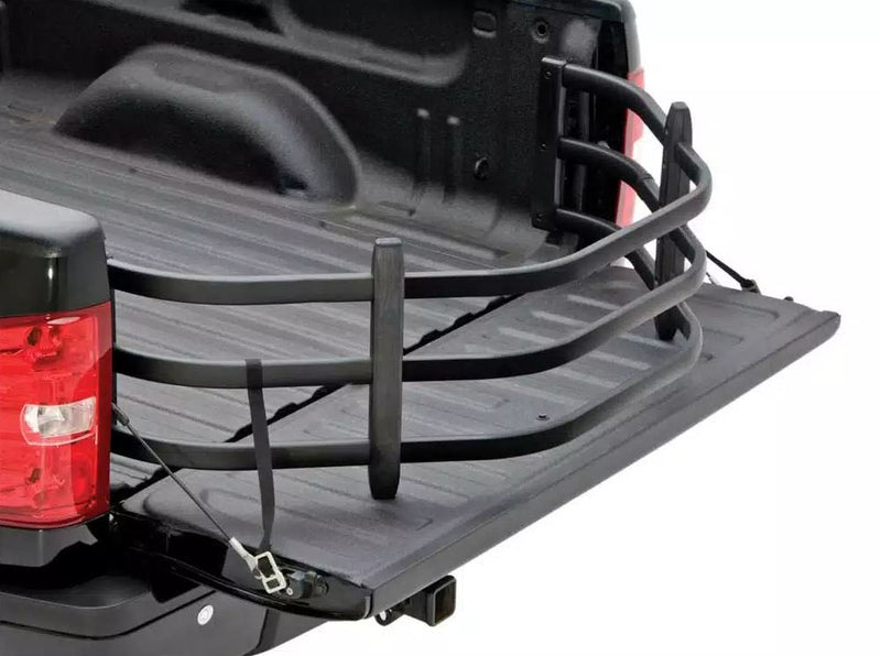 Black bed extender extended over the lowered tailgate of a black pickup, bed view