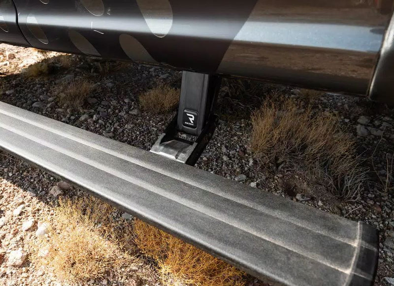 Running board deployed above desert scrub under a camouflage-wrapped vehicle
