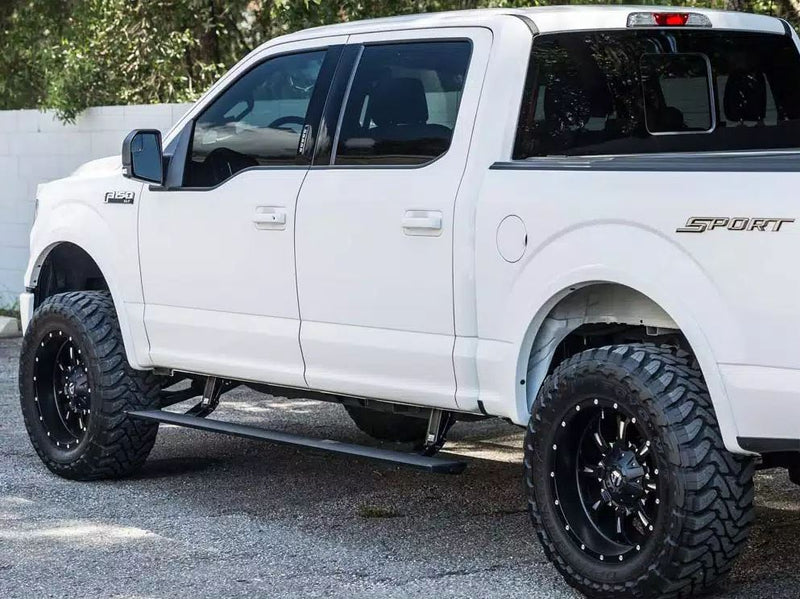 Lifted white crew-cab pickup with the PowerStep deployed, three-quarter side view on asphalt