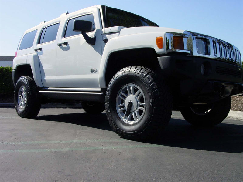 White SUV parked on asphalt with the running board stowed under the doors