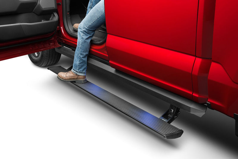 A person in jeans steps from the lit PowerStep XL into the open door of a red pickup