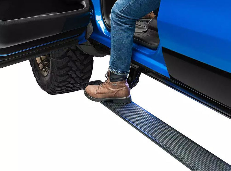 A boot steps onto the deployed running board of a blue pickup with the door open