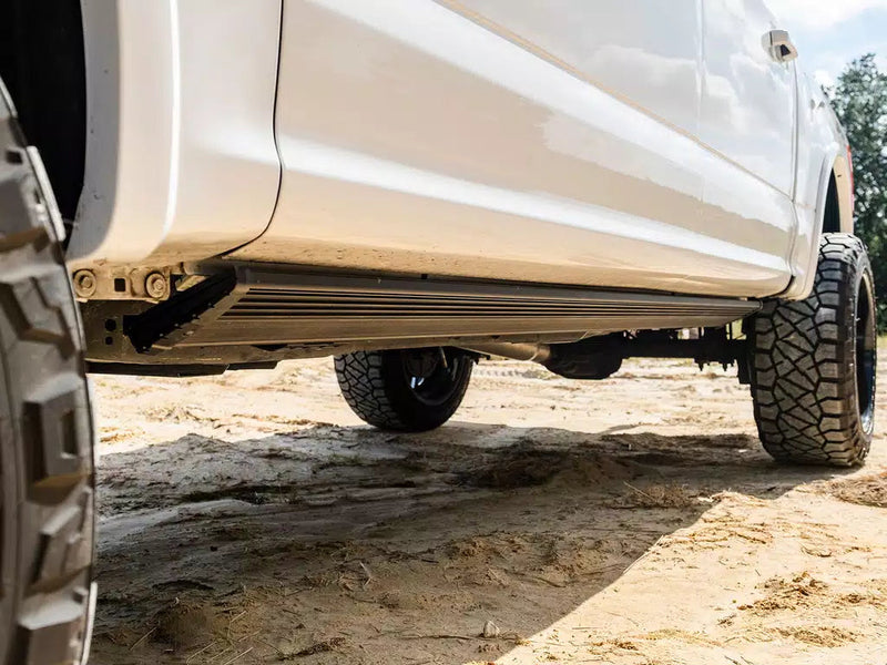 White pickup on sand with the PowerStep Xtreme board stowed flush under the rocker panel.