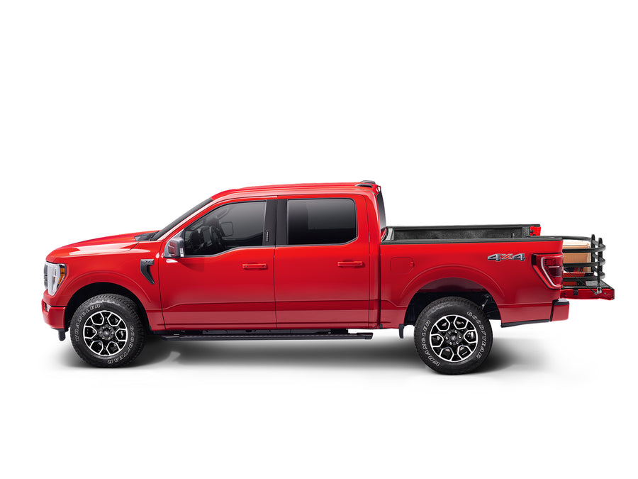 Side view of a red crew-cab pickup with the BedXTender HD Max extended past the tailgate, holding cargo