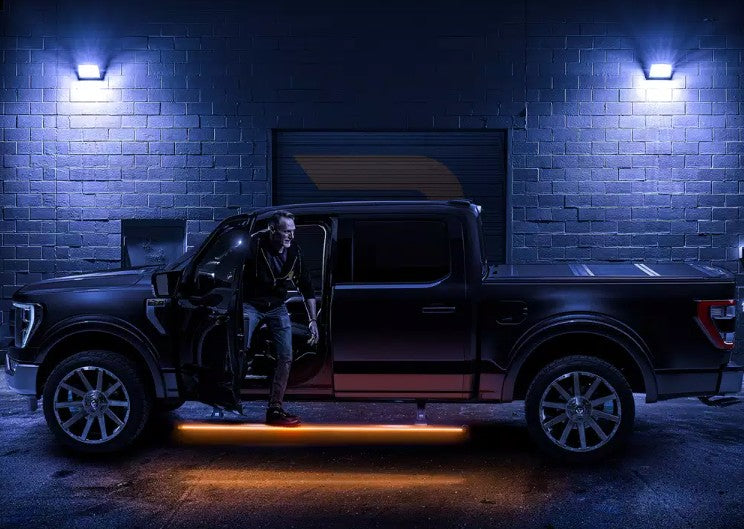 A man steps out of a dark pickup at night in a lit alley, the running board glowing amber