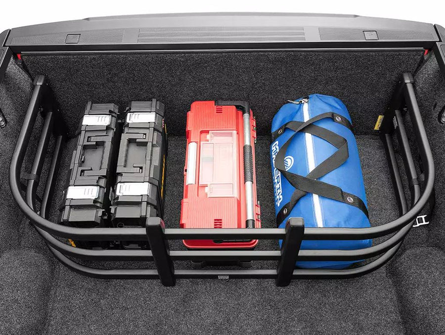 BedXTender HD Max corralling two cases, a red toolbox and a blue duffel against the closed tailgate