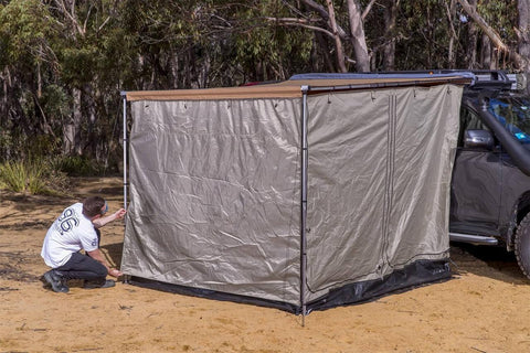 ARB awning room with floor being pegged out under an ARB awning on a grey 4WD, showing taupe walls and dark waterproof floor