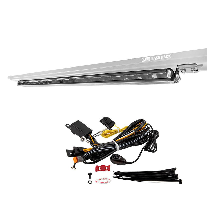 ARB BASE Rack Slimline LED light bar kit on white: the slim black light bar shown mounted under the edge of a BASE Rack, with a wiring loom, relay, inline fuse, rocker switch and cable ties laid out below