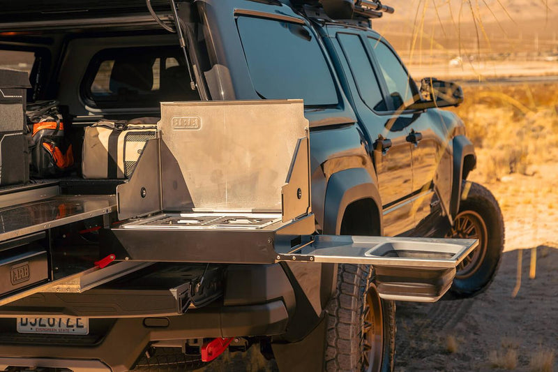 ARB slide-out camp kitchen with stove and sink deployed from the rear of a pickup