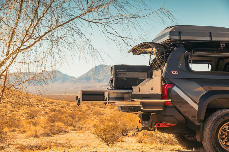 Pickup with a rooftop tent and an ARB slide-out camp kitchen deployed in the desert