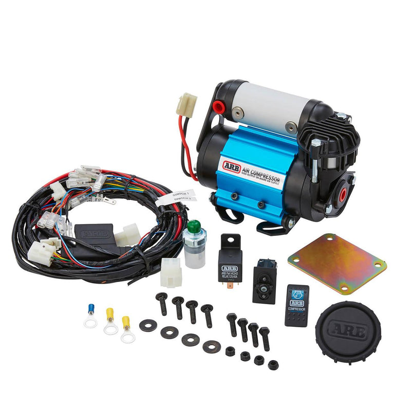 Complete ARB CKMA12 kit contents laid out: compressor, full wiring loom, 40A relay, illuminated dash switch, pressure switch, backing plate and mounting hardware