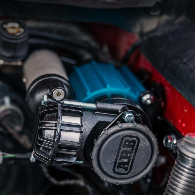 ARB CKMA12 compressor installed in an engine bay, showing the black filter housing with ARB cap and the blue motor body tucked against the fender