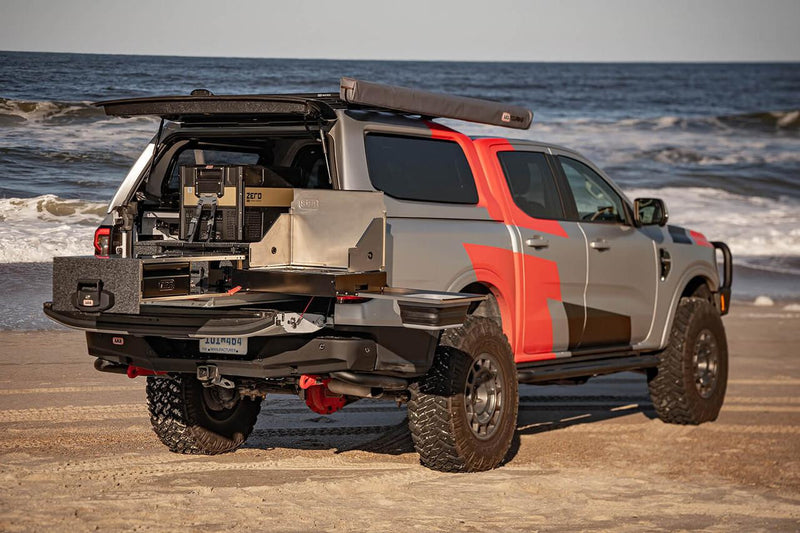 ARB Slide Out Camp Kitchen RDKNA1355 extended from the tray of a grey Ford Ranger on a beach, alongside an ARB drawer system and ZERO fridge