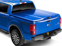 UnderCover Elite LX one-piece tonneau cover closed and latched on a pickup bed, rear three-quarter studio view, the lid sitting flush across the tailgate with no bed floor showing.