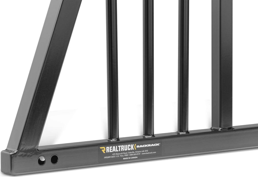 BackRack Three Round Headache Rack: Close-up of a black headache rack lower corner with vertical bars and a RealTruck BackRack product plate.