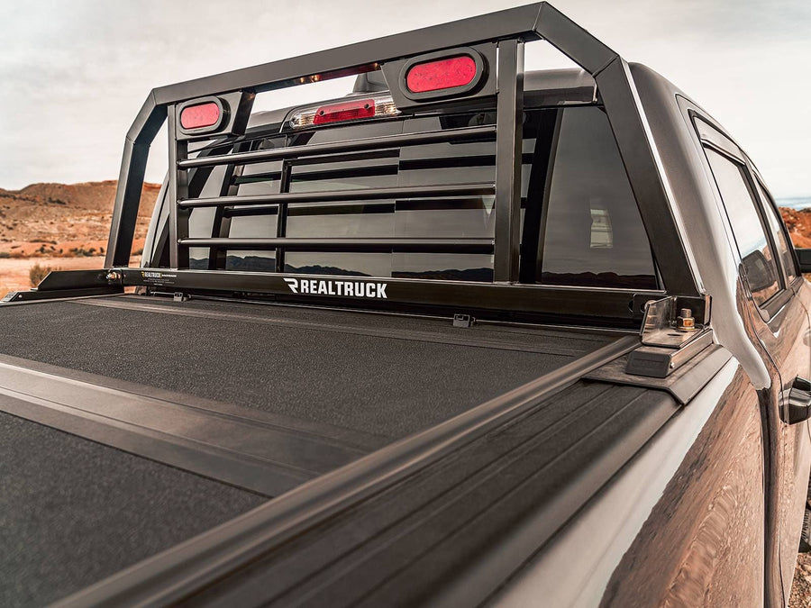BackRack SRL Headache Rack with Lights: A black SRL headache rack with red oval lights stands behind a dark truck cab above a hard folding tonneau cover.