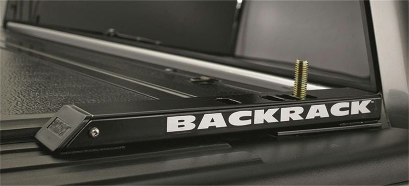 BackRack Tonneau Cover Riser Kit: Black tonneau riser rail lettered BACKRACK on a truck bed rail over a tonneau cover.