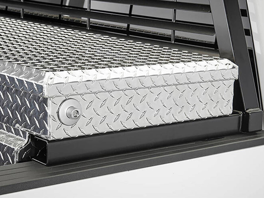 BackRack Crossover Toolbox Installation Kit: Black rack raised on toolbox brackets behind a polished diamond plate crossover toolbox on a white truck.