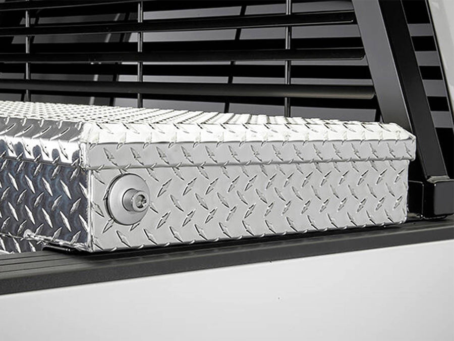 BackRack Low Profile Installation Kit: Black rack mounted on low profile brackets just behind a diamond plate crossover toolbox on a white truck.