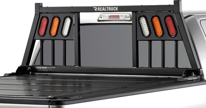BackRack Three Light Headache Rack: Black Three Light headache rack with three light openings mounted behind the cab of a pickup, seen from the rear quarter.