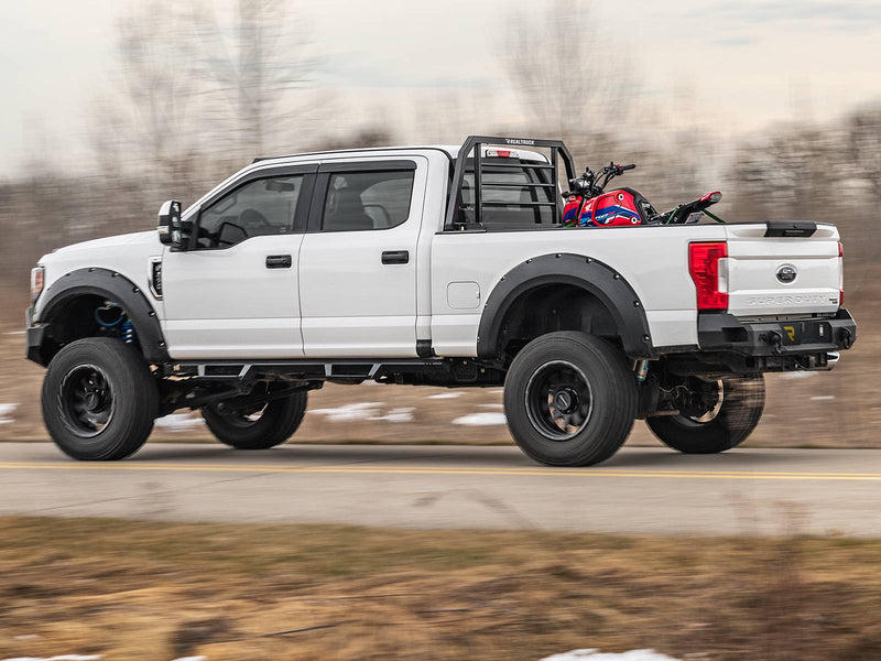 BackRack SR: A white Ford Super Duty with a black SR headache rack drives down a road carrying a red minibike