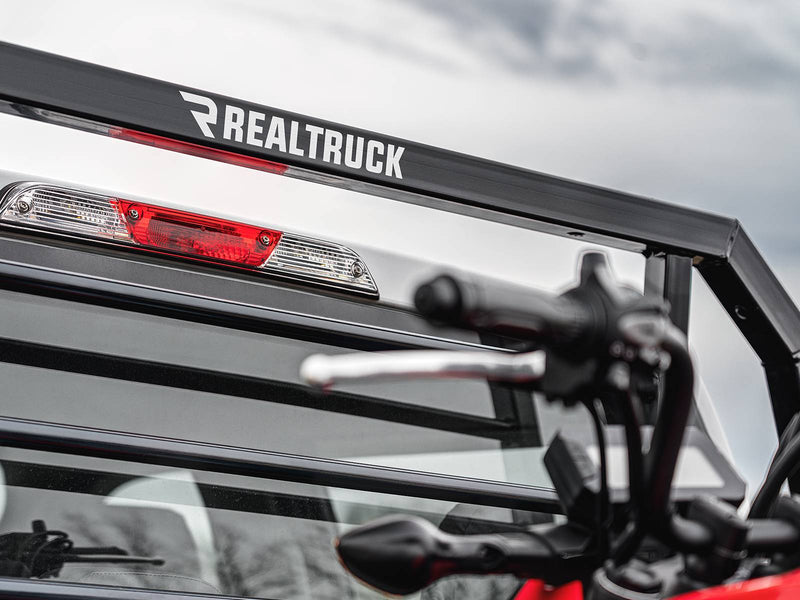 BackRack SR: close-up of the top bar of a black headache rack behind a cab, with a minibike handlebar in the foreground