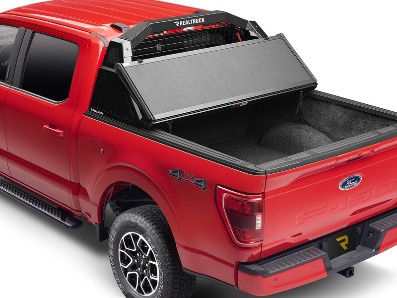 BackRack Trace Rack: A red Ford F-150 with a black Trace Rack behind the cab and a tonneau cover folded open over a carpeted bed