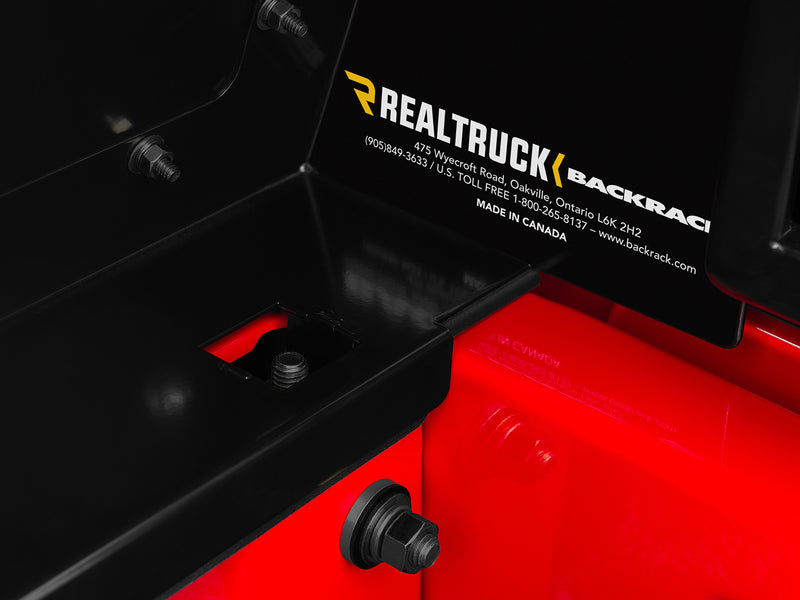 BackRack Trace Rack: close-up of a black rack side box interior with mounting hardware and a RealTruck BackRack product plate