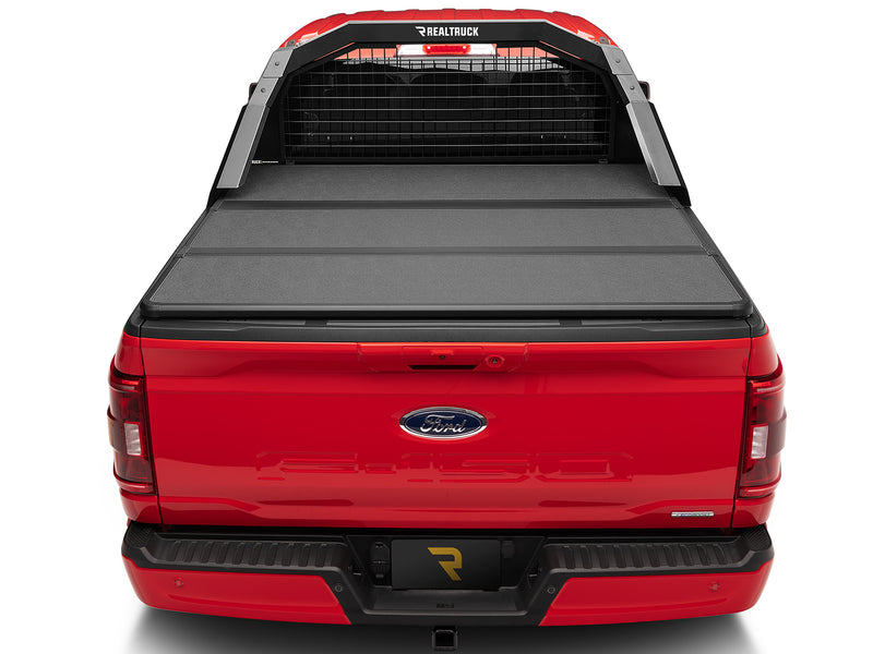 BackRack Trace Rack: rear view of a red Ford F-150 with a black Trace Rack behind the cab and a hard folding tonneau cover