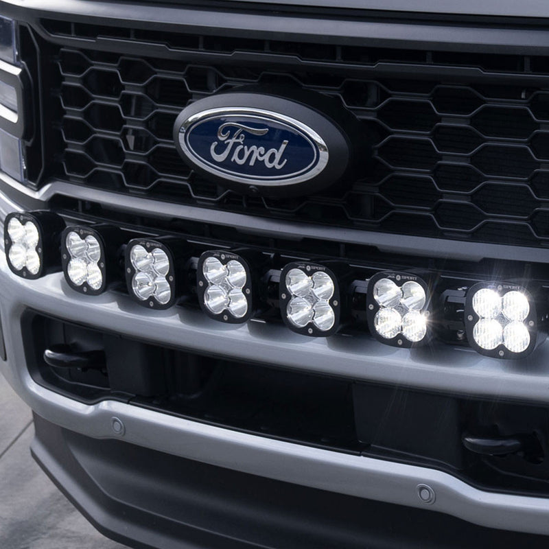 Baja Designs 7XL Linkable Bumper Light Kit on a Ford Super Duty: close view of a late-model Ford Super Duty grille with seven lit XL pods along the front bumper