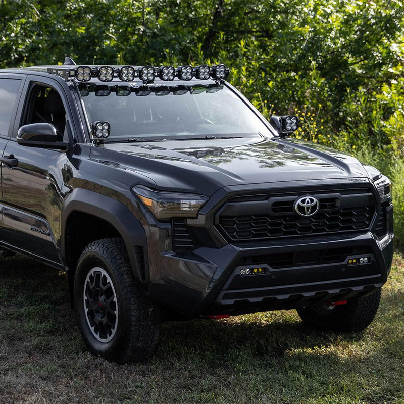 Baja Designs 8XL Linkable Roof Kit installed on a Toyota Tacoma: A gray Toyota Tacoma parked on grass carries an eight-pod linkable LED roof bar and A-pillar pods