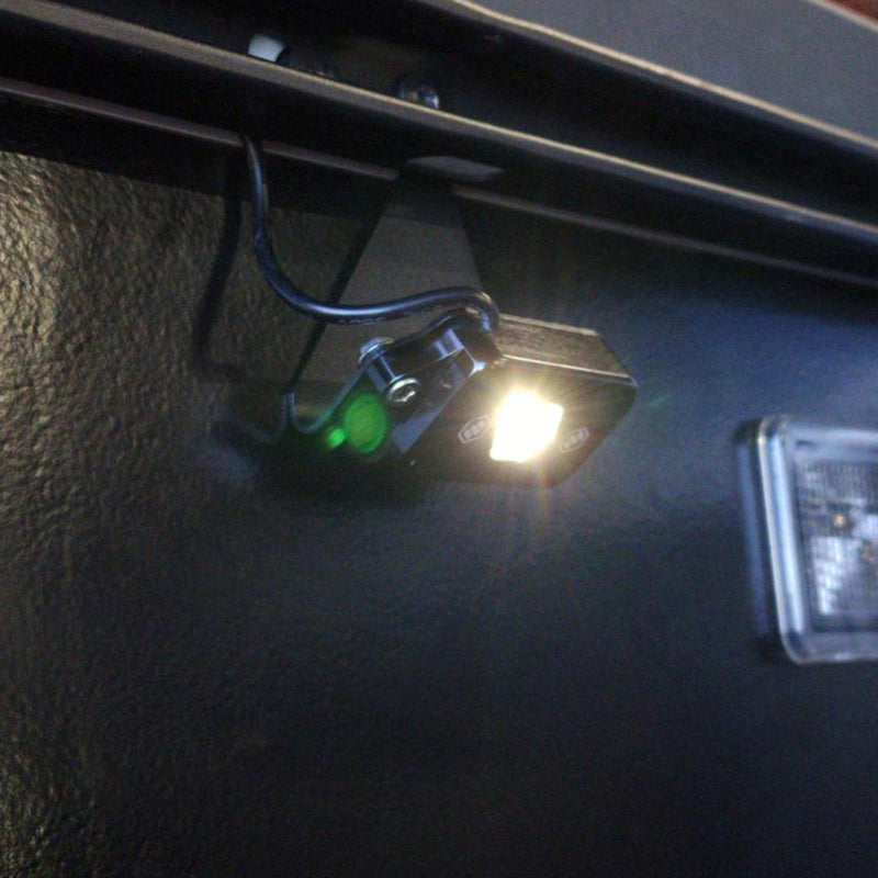 Baja Designs Cargo Light Kit on a vehicle: A small LED cargo light glowing white under a truck bed rail at night