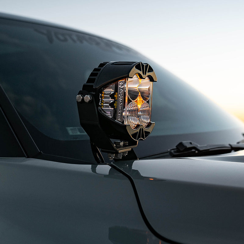 Baja Designs LP4 Pro A-Pillar Light Kit on a vehicle: A Baja Designs LP4 Pro LED pod with a glowing amber backlight mounted on the A-pillar of a gray truck