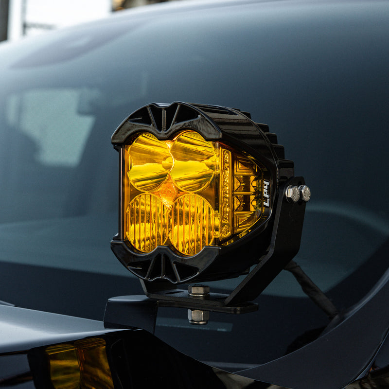 Baja Designs LP4 Pro LED Auxiliary Light Pod on a vehicle: an LP4 Pro LED pod with amber lenses mounted on a hood-edge bracket of a dark blue vehicle