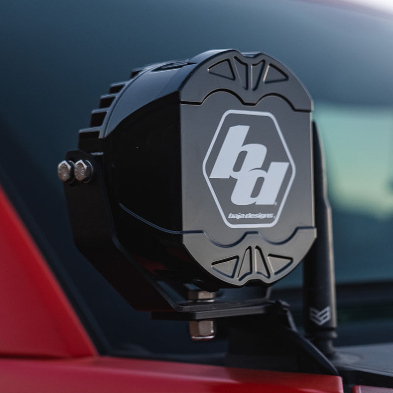 Baja Designs LP4 Single Rock Guard on a vehicle: an LP4 light wearing a black Baja Designs rock guard mounted on a red vehicle, vehicle not identifiable