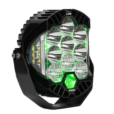Baja Designs LP9 Pro LED Auxiliary Light Pod, whole product on a studio background: front three-quarter view of a single black LP9 Pro LED light pod clear lens, driving combo optics, green backlight glowing on its mounting bracket against a white