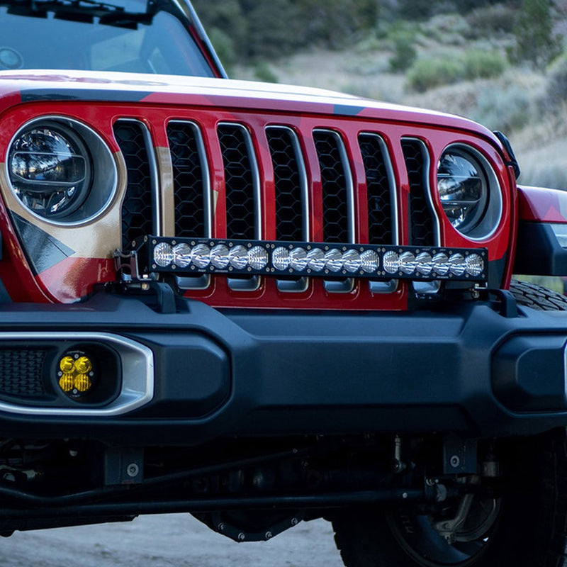 Baja Designs OnX6+ 30" Bumper Light Kit on a Jeep Wrangler JL: front view of a red Jeep with a 30" OnX6+ light bar on the bumper below the seven-slot grille and an amber fog pod