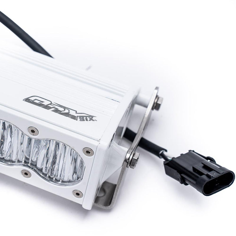 Close-up of the Baja Designs OnX6+ White Straight LED Light Bar: close view of the end of a white LED light bar with its bracket, OnX6 logo and wiring connector