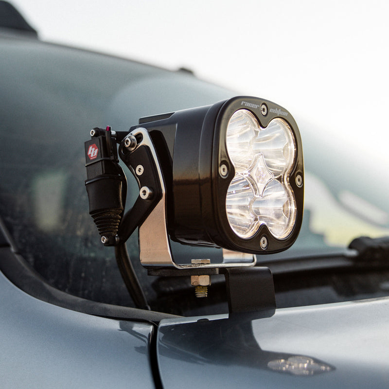 Baja Designs REFLEX Light Actuator Kit, XL Standard Housing on a vehicle: an XL Racer Edition pod with clear lens and the REFLEX actuator on a hood-mount bracket on a gray vehicle