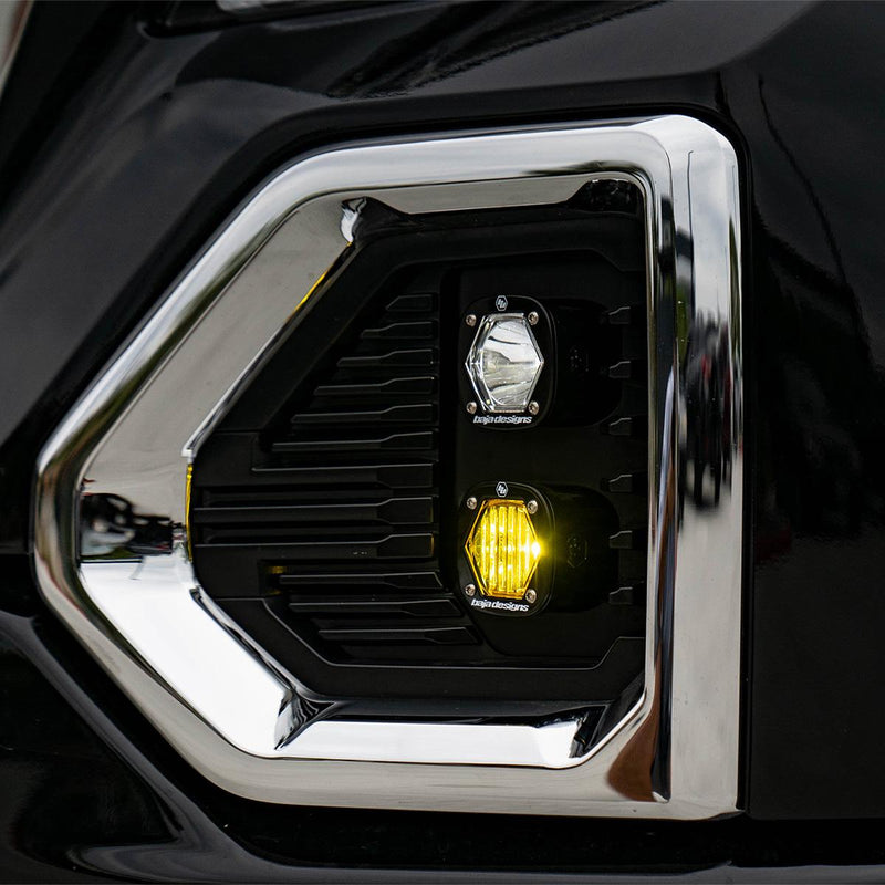 Baja Designs S1 Dual Fog Pocket Light Kit on a GMC Sierra 1500: clear S1 pod above a glowing amber S1 pod in the chrome-trimmed fog pocket of a black GMC Sierra