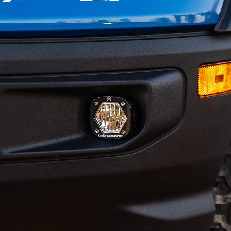 Baja Designs S1 Fog Pocket Light Kit on a vehicle: close view of a clear S1 pod set in a black plastic fog pocket next to an amber side marker