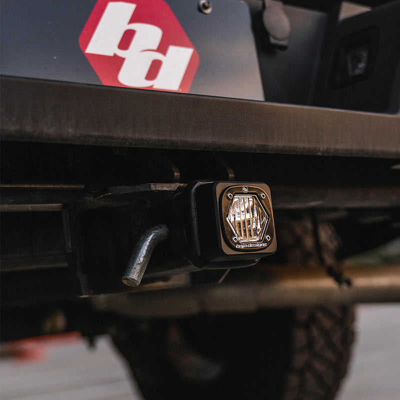 Baja Designs S1 Universal Hitch Light Kit on a vehicle: close view of an S1 hitch light seated in a rear receiver with a hitch pin, a red Baja logo decal above