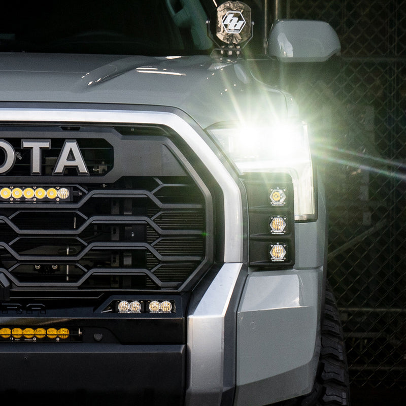 Baja Designs S1 Vent Kit on a Toyota Tundra: A close view of a silver Toyota Tundra front corner with small LED pods glowing in the bumper vent beside the headlight