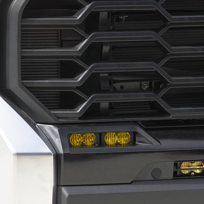 Baja Designs S2 Sport Dual Fog Pocket Light Kit on a Toyota Tundra: two S2 pods with amber lenses fitted in the lower fog opening beside the grille of a silver Toyota Tundra