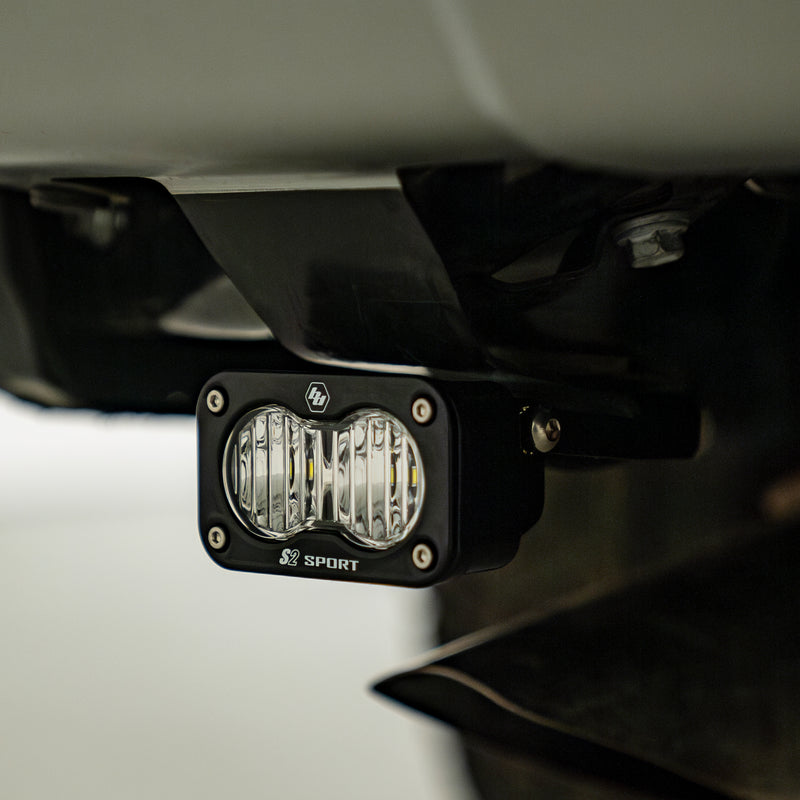 Baja Designs S2 Sport Reverse Kit on a vehicle: S2 Sport LED pod mounted on a bracket beneath a vehicle rear bumper