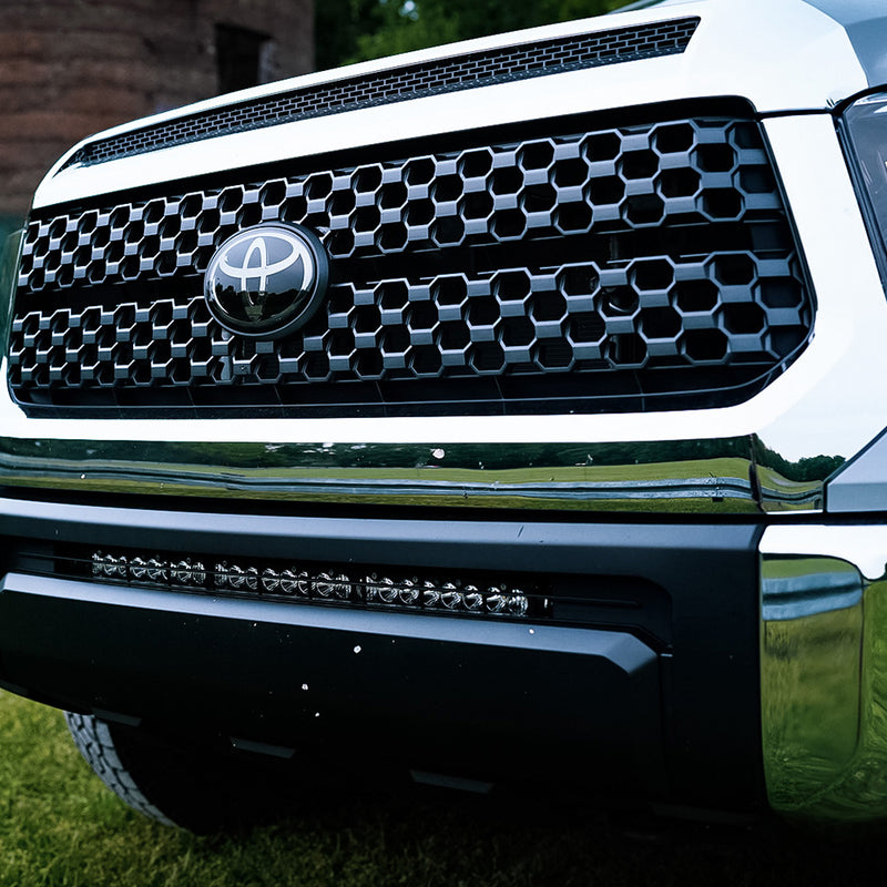 Baja Designs S8 30" Grille Lower Light Kit on a Toyota Tundra: close view of a white Toyota Tundra front end with an S8 light bar fitted in the lower grille opening