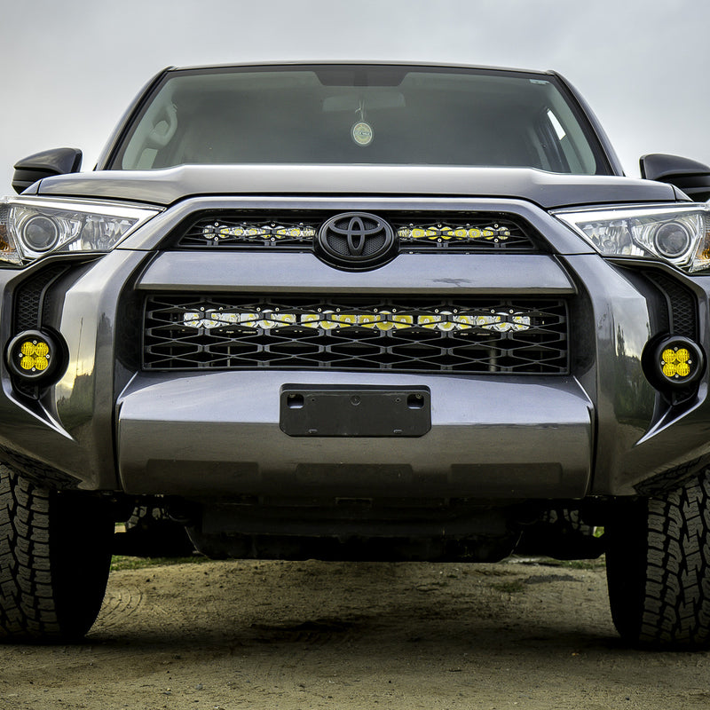 Baja Designs S8 Dual 10" Grille Upper Light Kit installed on a Toyota 4Runner: front view of a gray Toyota 4Runner with two lit light bars across the upper grille and amber pods in the fog pockets